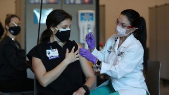 a woman receives her first dose of the COVID-19 vaccine at a hospital