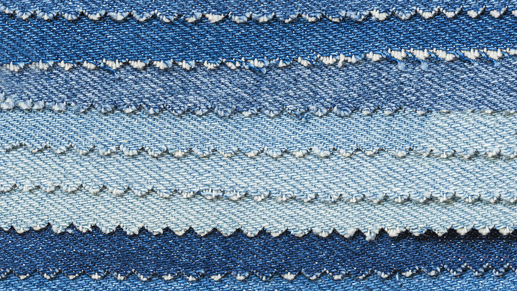 several pieces of denim dyed different shades of blue are fanned out on top of each other