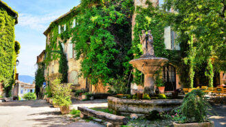 a European courtyard with building covered in greenery