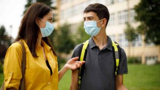 a photo of a mom and son talking, they are both wearing masks