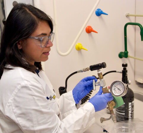 a young woman wearing a lab coat and purple gloves is showing the vaccine delivery device