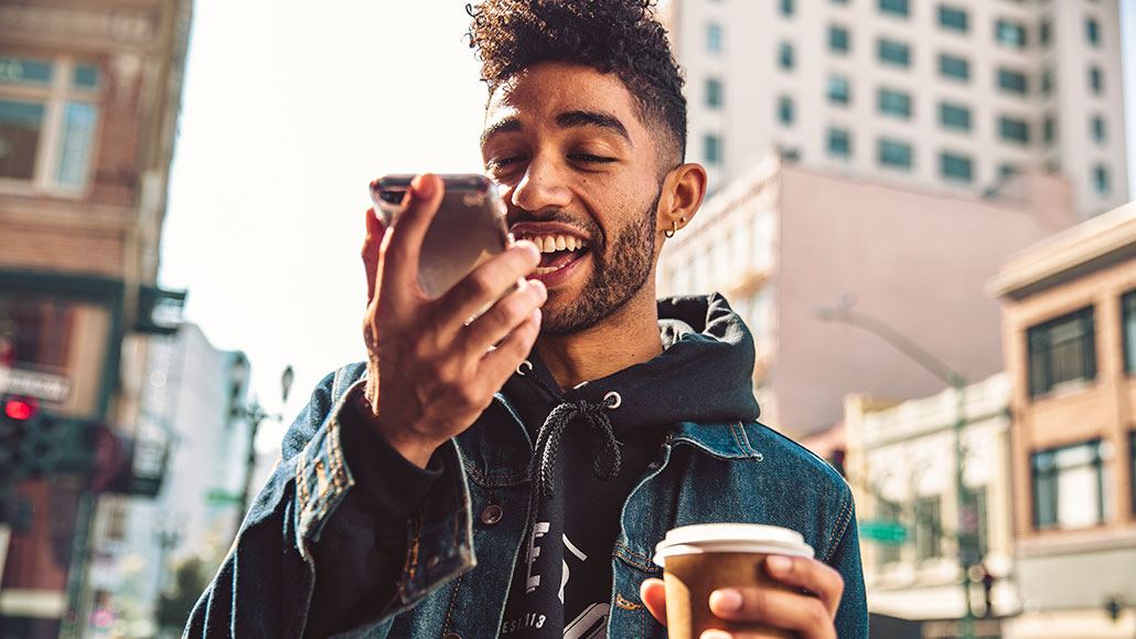 an african american man is holding a phone to his mouth and speaking into it