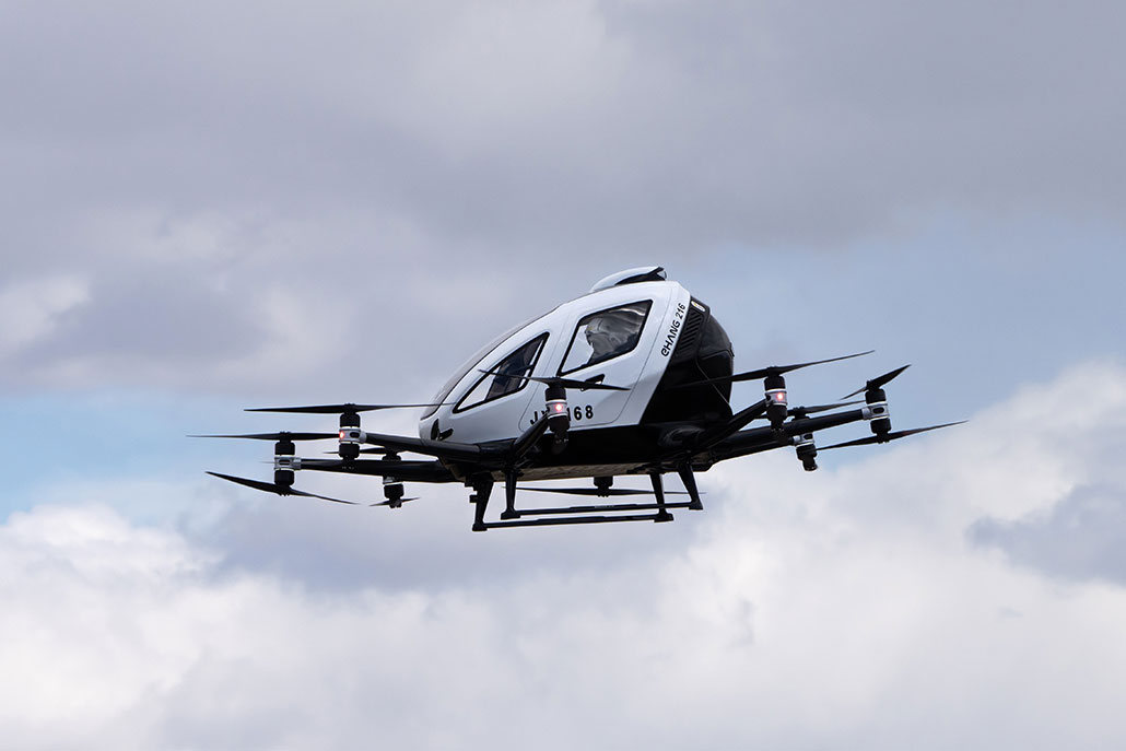 a picture of a flying car in the sky. the vehicle has multiple horizontal propellers on arms radiating out from the bottom of the vehicle