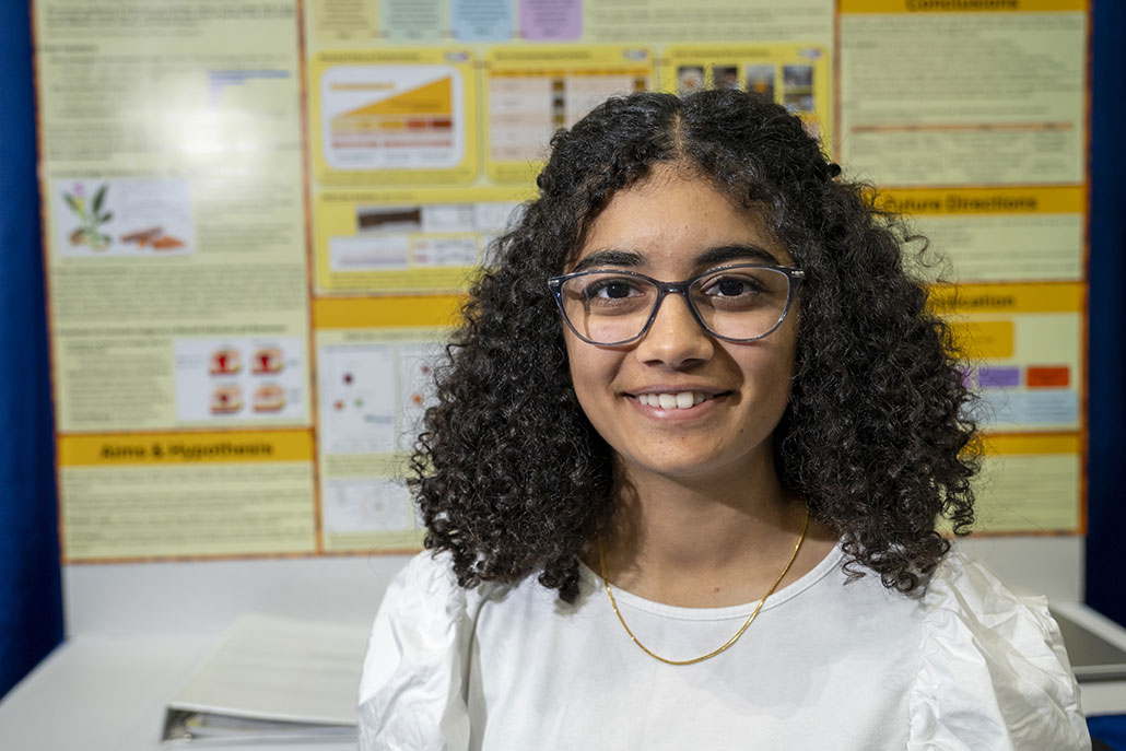 a photo of Ishita Mukadam in front of her project board at ISEF 2023