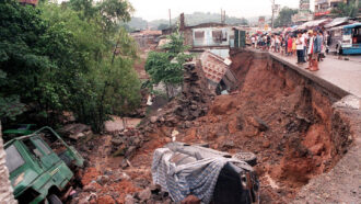 people in the Philippines stand on the edge of a road that collapsed due to a mudslide