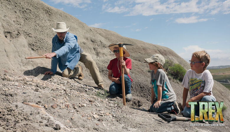 Dr. Lyson describes the fossil to the three boys who are all sitting on the rocks looking at the fossil.